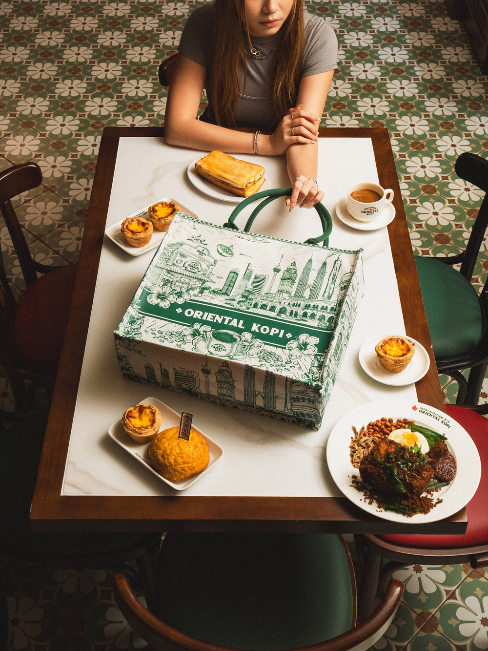 Christy Ng x Oriental Kopi tote on a kopitiam table with egg tarts and polo bun